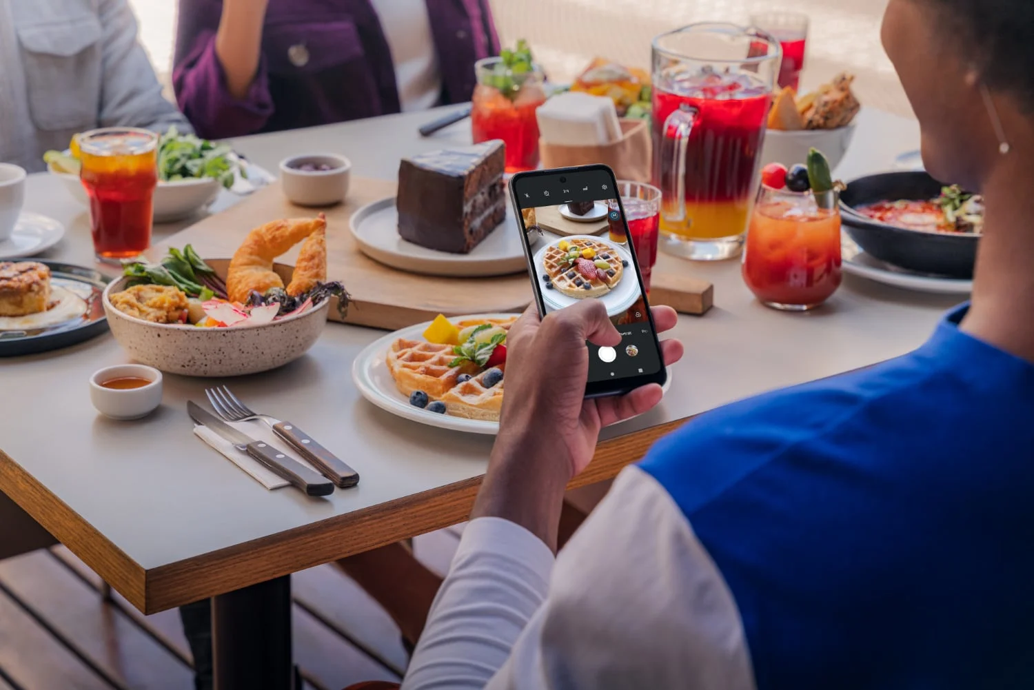 A person using the Moto G Play to take photos of waffles at a fancy breakfast.