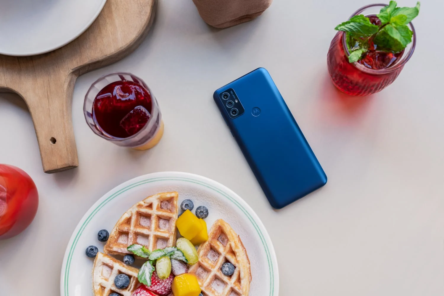 Smartphone económico Moto G Play en una mesa con desayuno.