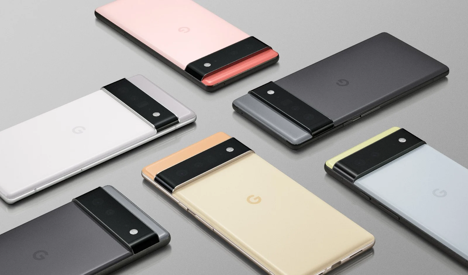 Six Google Pixel 6 and Pixel 6 Pro devices laying on a grey surface at various angles, perpendicular to each other.