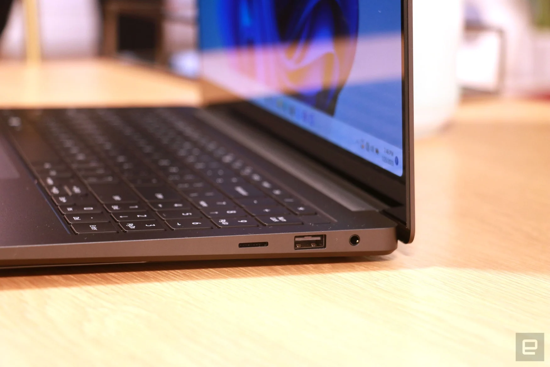 A close up of the side view of the Galaxy Book 3 Ultra. In view are the USB-A port and a headphone jack, as well as the keyboard's buttons that have minimal depth.
