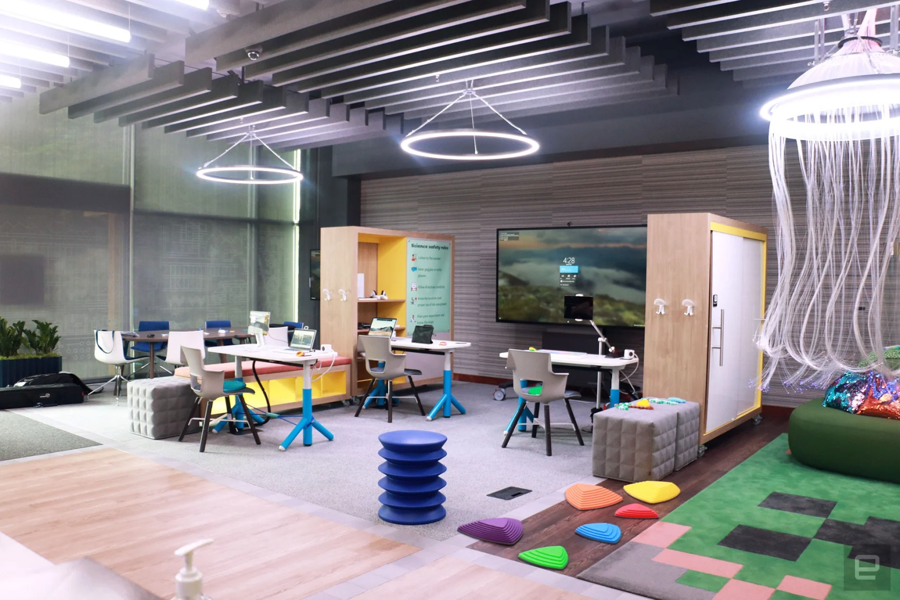 The right side of Microsoft's new Inclusive Tech Lab, where there  are colorful pieces of furniture scattered across three sections. On the right is a pseudo jellyfish fixture hanging from the ceiling.