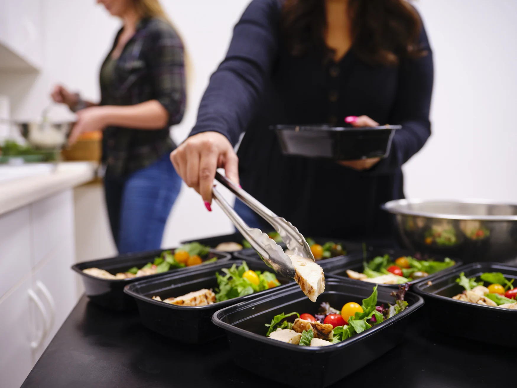 A woman prepares a healthy meal in her kitchen, using a scale to portion the ingredients.