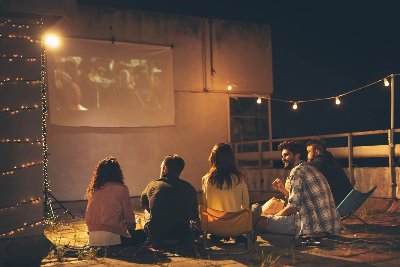 Friends watching a movie on a building rooftop terrace