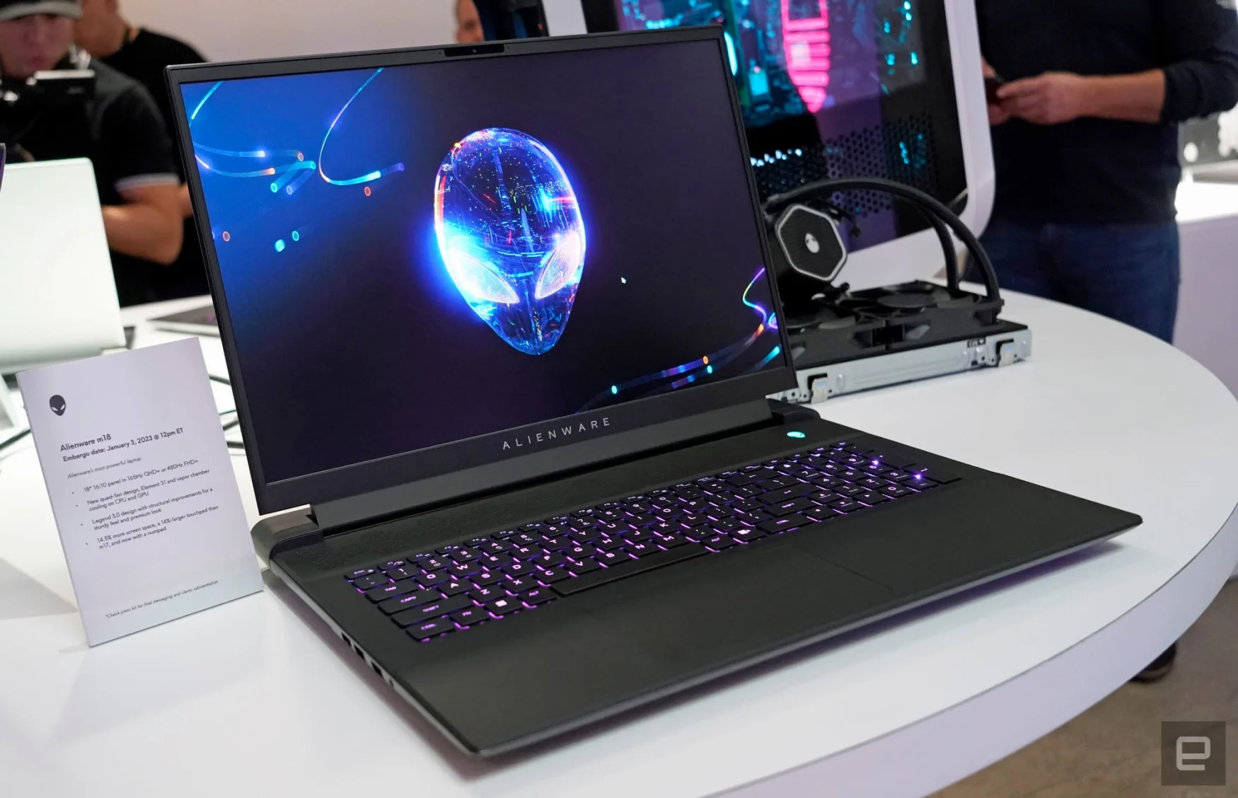 CES showcase image of the Alienware m18 laptop.  The dark laptop sits on a white table with an alien logo on the screen.