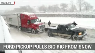 Ford pickup tows semi trucks out of snow bank during snowstorm